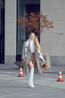 A tall model walks down a modern city street, showcasing chic winter fashion with a stylish