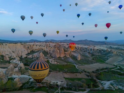 Aerial view of balloons over a vast landscape at sunrise in Cappadocia, aerial view, Göreme