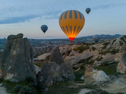 Hot air balloons hovering over a rocky landscape at dawn in Cappadocia, aerial view, Göreme