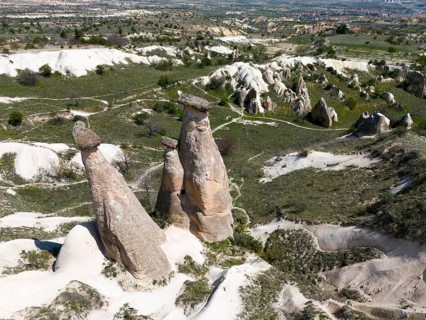 High rock formations in hilly landscape with green areas, aerial view, fairy chimneys near Ürgüp,