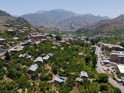 Panoramic view of a village along a road amidst green hills and mountains, aerial view, Meghri,