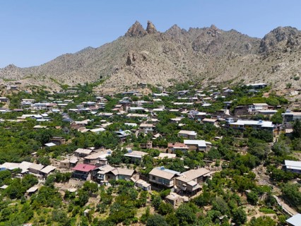 Traditional mountain village with scattered houses and hills surrounded by mountains, aerial view,