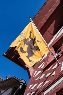 Cantonal flag of Schaffhausen on a half-timbered house, pictogram of a black goat striding freely