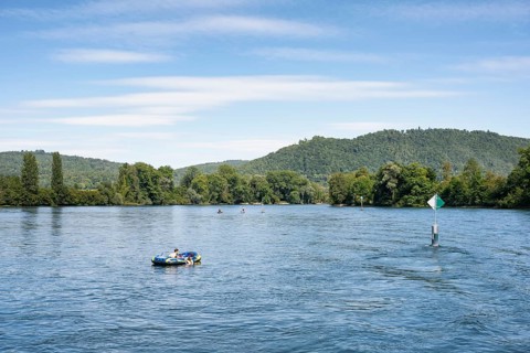 Inflatable boat, stand up paddler, swimming next to a fairway on the Rhine, Hochrhein near
