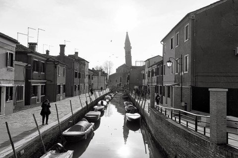 Strollers along the canal, typical street scene in winter, monochrome, facades in Burano, leaning
