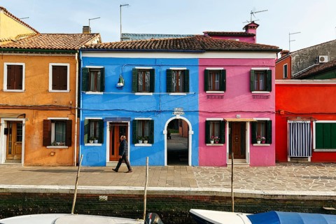 Lone walker on the canal, typical street scene in winter, colourful facades in Burano, island in