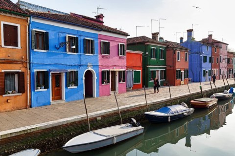 Lone walkers on the canal, typical street scene in winter, colourful facades in Burano, island in