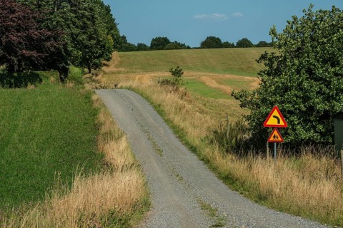 Curvy small gravel road with road sign in Ystad municipality, Skåne county, Sweden, Scandinavia