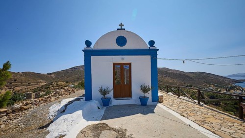 White and blue chapel in a rural area with views of the sea and surrounding hills, Panagia tou