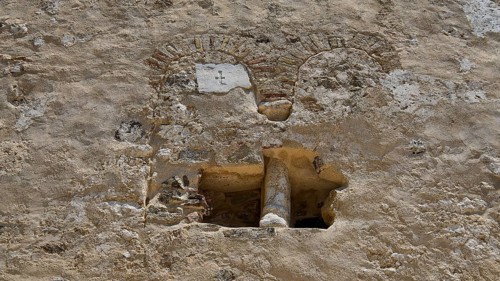 Close-up of a historic stone wall with rustic details, built-in antique column, basilica, church,