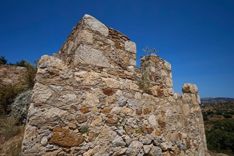 Old stone ruins in a Mediterranean landscape under a clear sky with sparse vegetation, Panagia tou