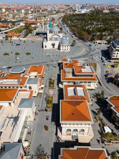 Bird's eye view of an urban landscape with red roofs and a mosque in the background in sunny
