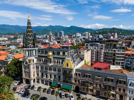 Charming city with historic architecture against a backdrop of mountains and blue sky, aerial view,