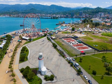 Aerial view of a harbour area with Ferris wheel, lighthouse and town by the sea, surrounded by