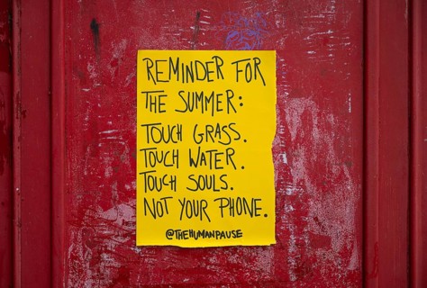 Yellow poster on phone box reminds people to appreciate nature and put their mobile phones away,