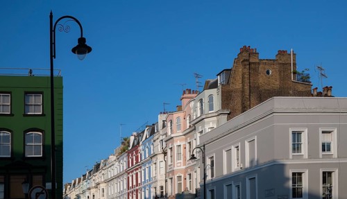 Terraced houses, townhouses with different, colourfully painted facades under a blue sky,