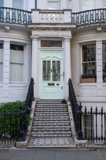 House entrance with mint green door, black and white staircase and decorative wrought iron