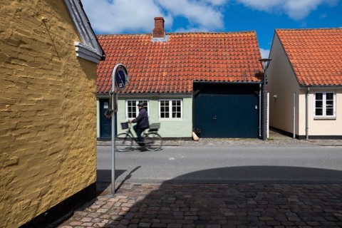 Cyclist on sunny street with colourful brick houses, Old Town, Ringkøbing, Ringkøbing Fjord,