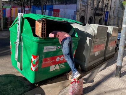Poverty in Buenos Aires, a homeless man searches for something usable in a rubbish container,