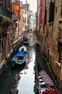 Strollers on a small bridge, boats on a canal, typical street scene in Venice, Italy