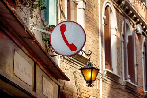 Sign with pictogram, red telephone receiver, public telephone, facade of a restaurant with street