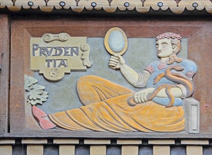 Allegorical wood carving with figure of Prudentia, symbol of prudence and reason, mirror, snake