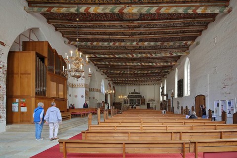 Interior view of the Church of the Holy Spirit with painted wooden ceiling, wooden beams, organ,