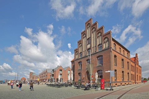 Brick building with stepped gable at the harbour and pedestrians, tourists, houses, stepped gable,