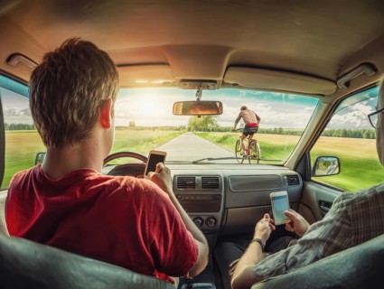 A car driver and his passenger look at their smartphones while driving and endanger themselves and