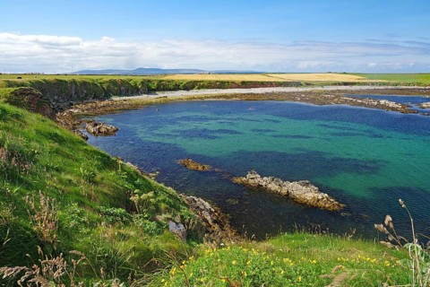 Picturesque bay with clear water, surrounded by green cliffs and wide skies, Pierowal, Westray,