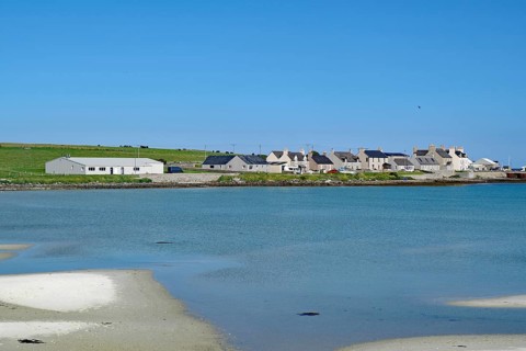 Small coastal village with houses on the waterfront under a blue sky, Pierowal, Westray, Orkney