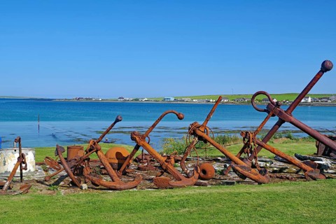 Rusty anchors in a meadow on the coast with sea in the background, Pierowal, Westray, Orkney