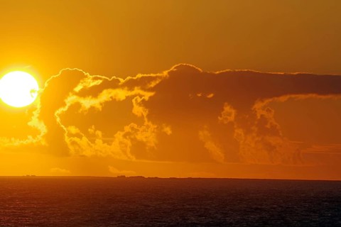 Sunset over the sea with bright sun and dramatic clouds, crossing between Orkney and Shetland