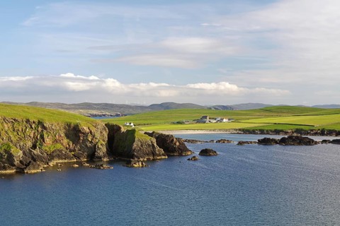 Coastal landscape with cliffs and green land under a slightly cloudy sky, Hillswick, Eshaness,