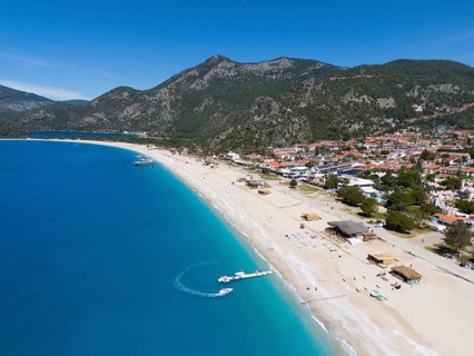 Aerial view of a long sandy beach with neighbouring town and mountainous background, aerial view,