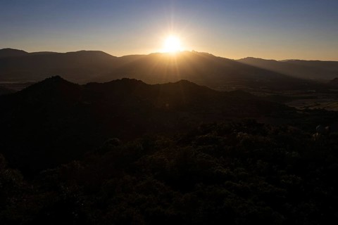The sun sets behind the mountains on the Mediterranean island of Sardinia, Monte Nai, Costa Rei,