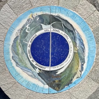 Top view of orientation board with description of mountain peaks on stone pedestal at viewpoint on