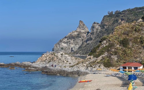 Rocky beach with parasols and buildings on the coast of the blue sea, Ricadi, Capo Vaticano