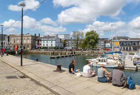 People sitting on quayside of marina harbour, The Barbican, Plymouth, Devon, England, UK