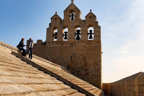 Bell tower of Notre-Dame-de-la-Mer church, two tourists enjoying the view from the roof of the