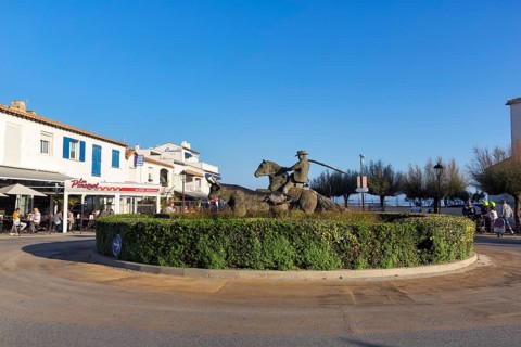 Roundabout with sculptures, cattle herder, guardian of the Camargue on a horse, next to a bull,