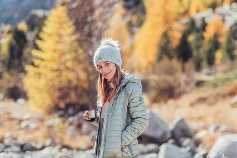 Woman in winter clothes in autumn Engadine with golden trees in Switzerland