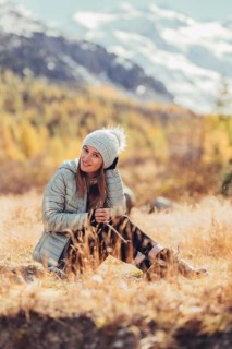 Woman in winter clothes in autumn Engadine with golden trees in Switzerland