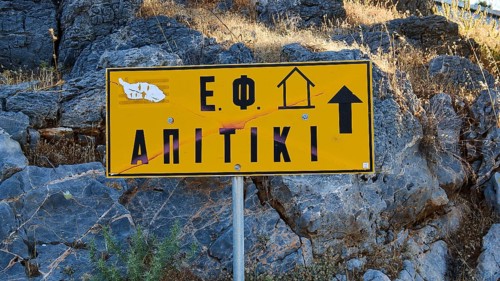Apitiki, Bunker, Yellow sign with Greek inscription and arrow in front of a rock face, Photos
