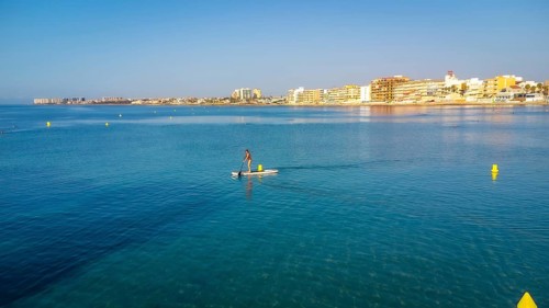 Calm waters and clear skies set the scene for a serene paddle boarding experience near a coastal