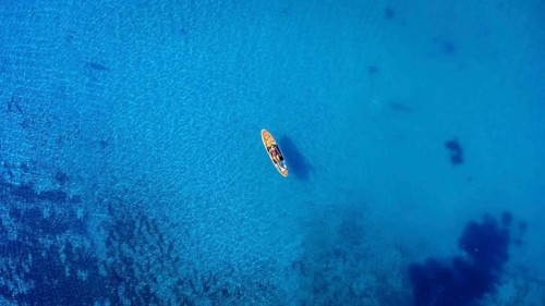 Aerial view of a sportswoman paddle surfing on a sup board in the transparent waters of the ocean