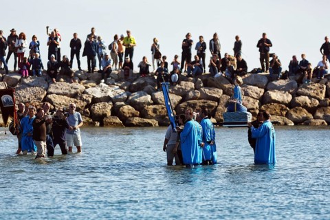 Pilgrimage, procession by the sea, pilgrims walking through water, statue of the Virgin Mary, crowd