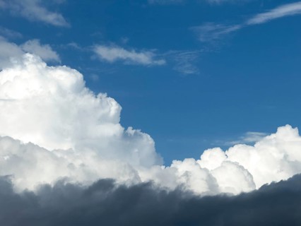 At the bottom of the picture grey nimbostratus clouds, above white cumulus cumulus clouds in front