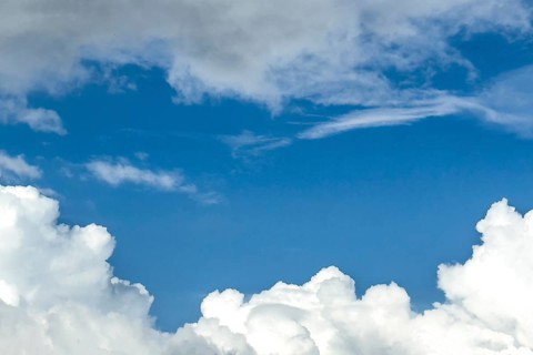 Below white cumulus clouds Cumulus clouds above grey stratocumulus framing blue sky, international