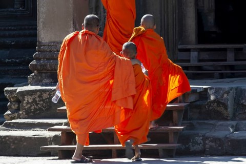 Buddhist monks and novices in orange monk's robes at the entrance to the Angkor Wat temple complex,